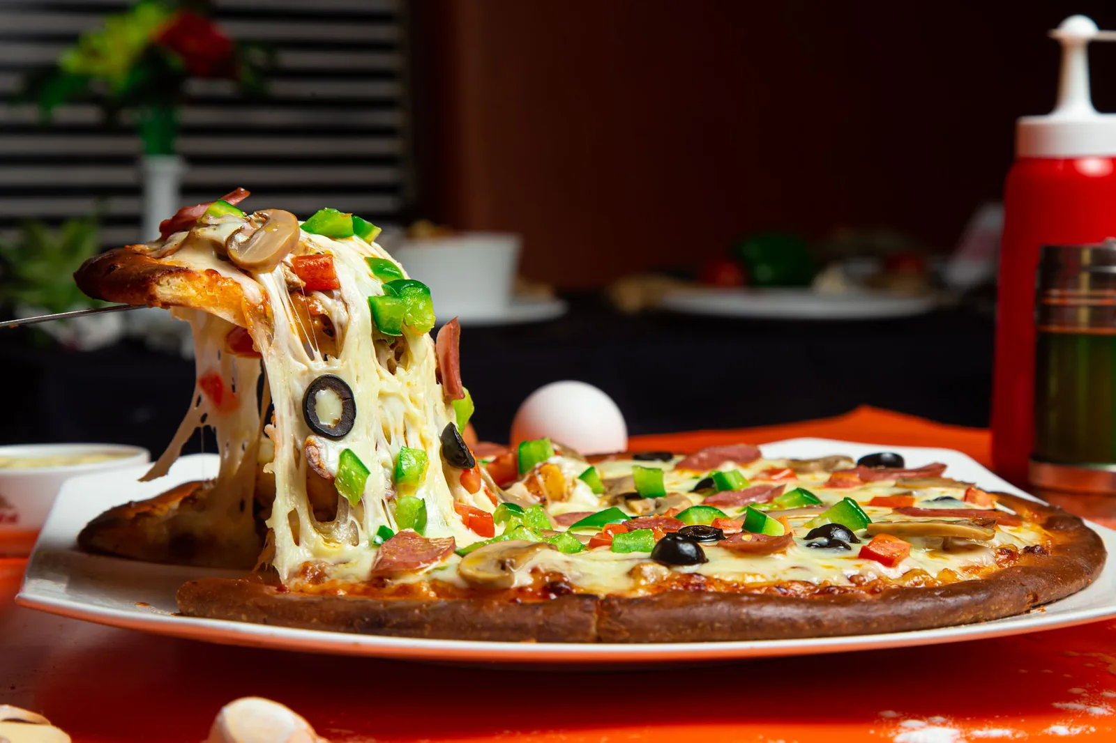 Pizza slice with mozzarella and toppings being lifted out of the pie