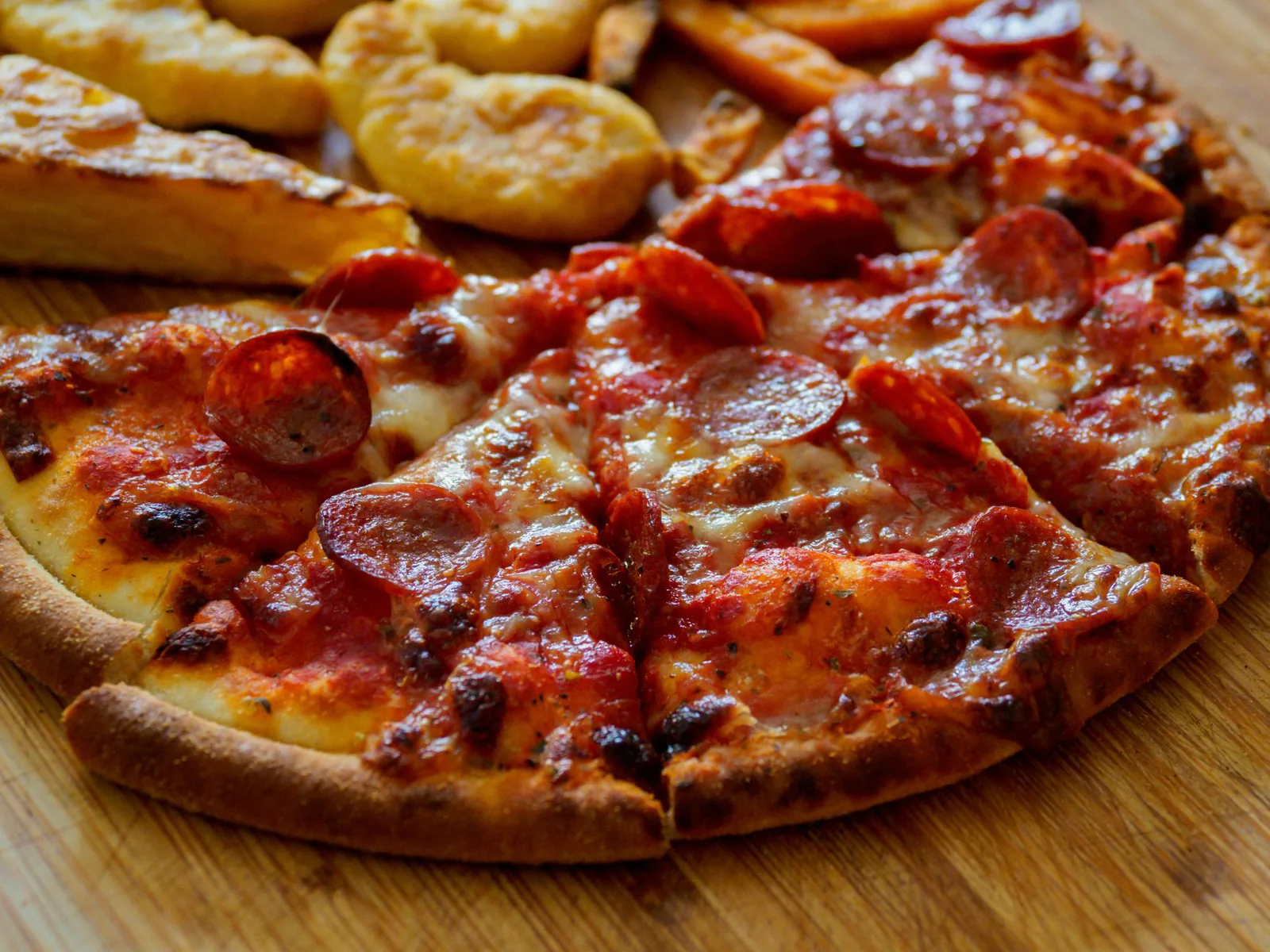 Pepperoni pizza with crispy cups on a wooden board