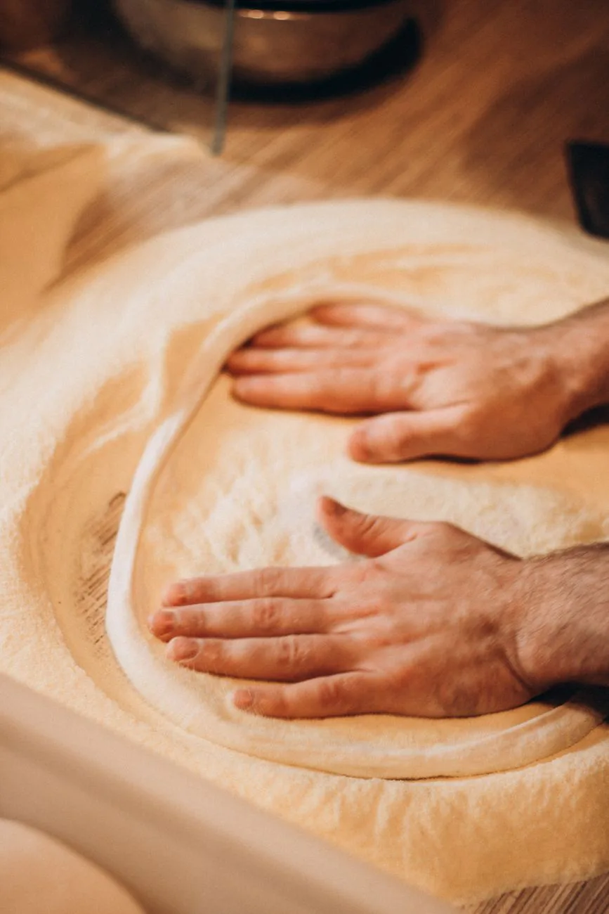 Hands shaping Big D Pizza dough on a floured surface