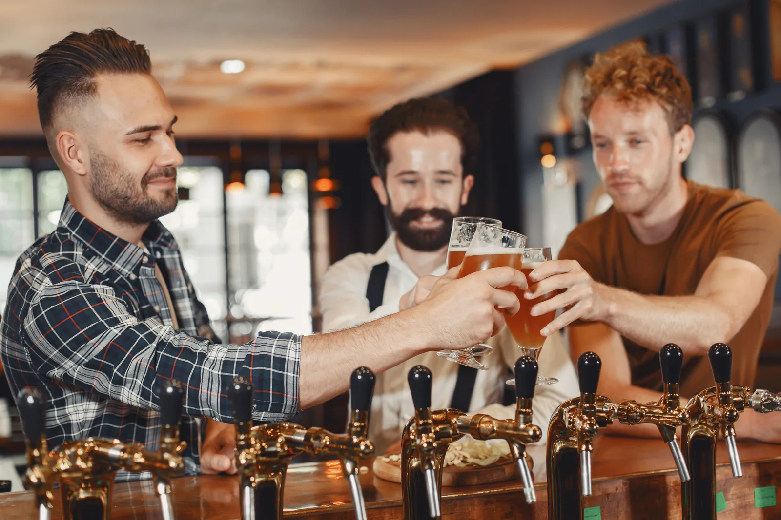 Friends toasting with cold drafts at the bar