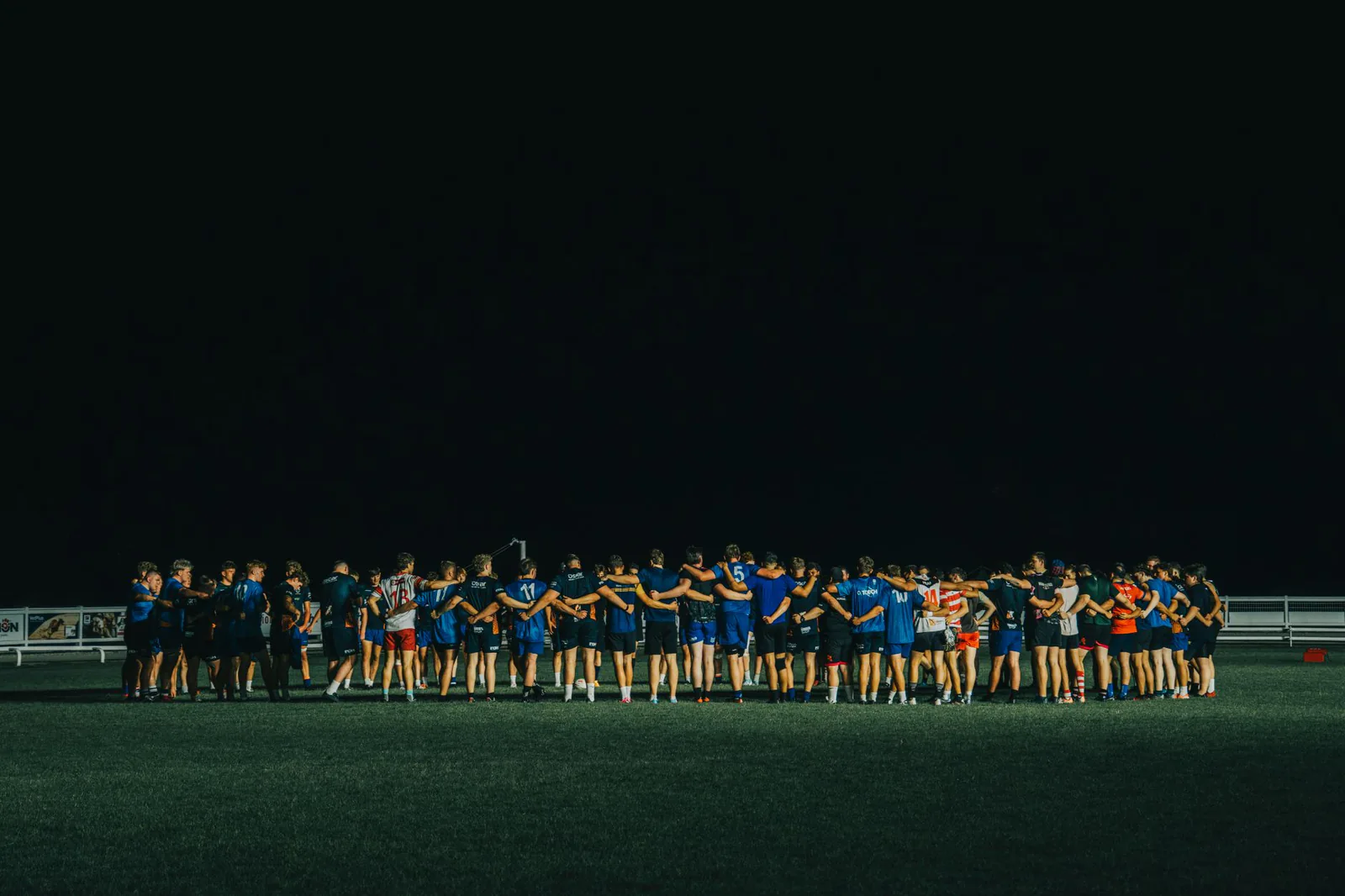 Team huddle on the field at night