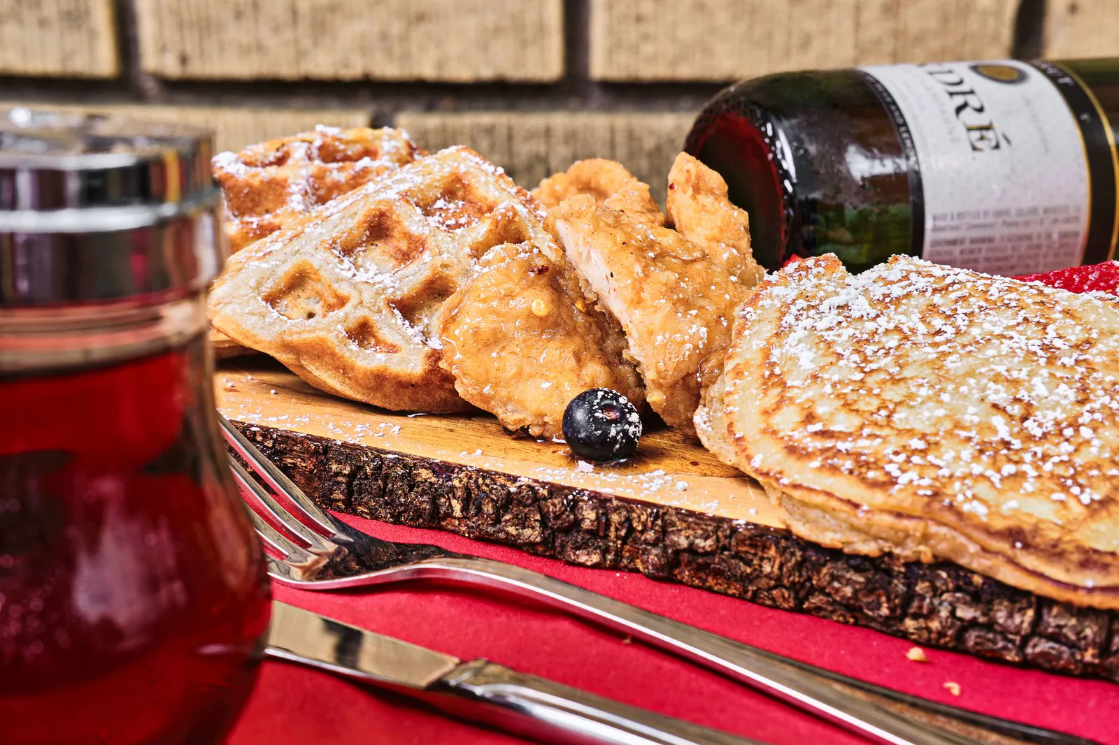 A wooden board overflowing with fried chicken, waffles and pancakes