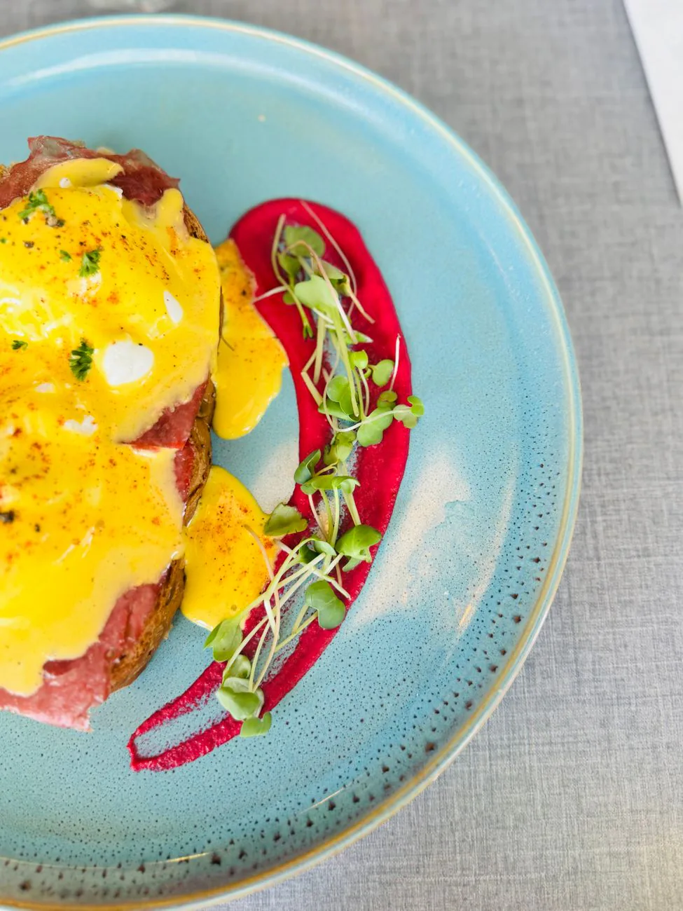 Eggs Benedict with hollandaise on a blue plate