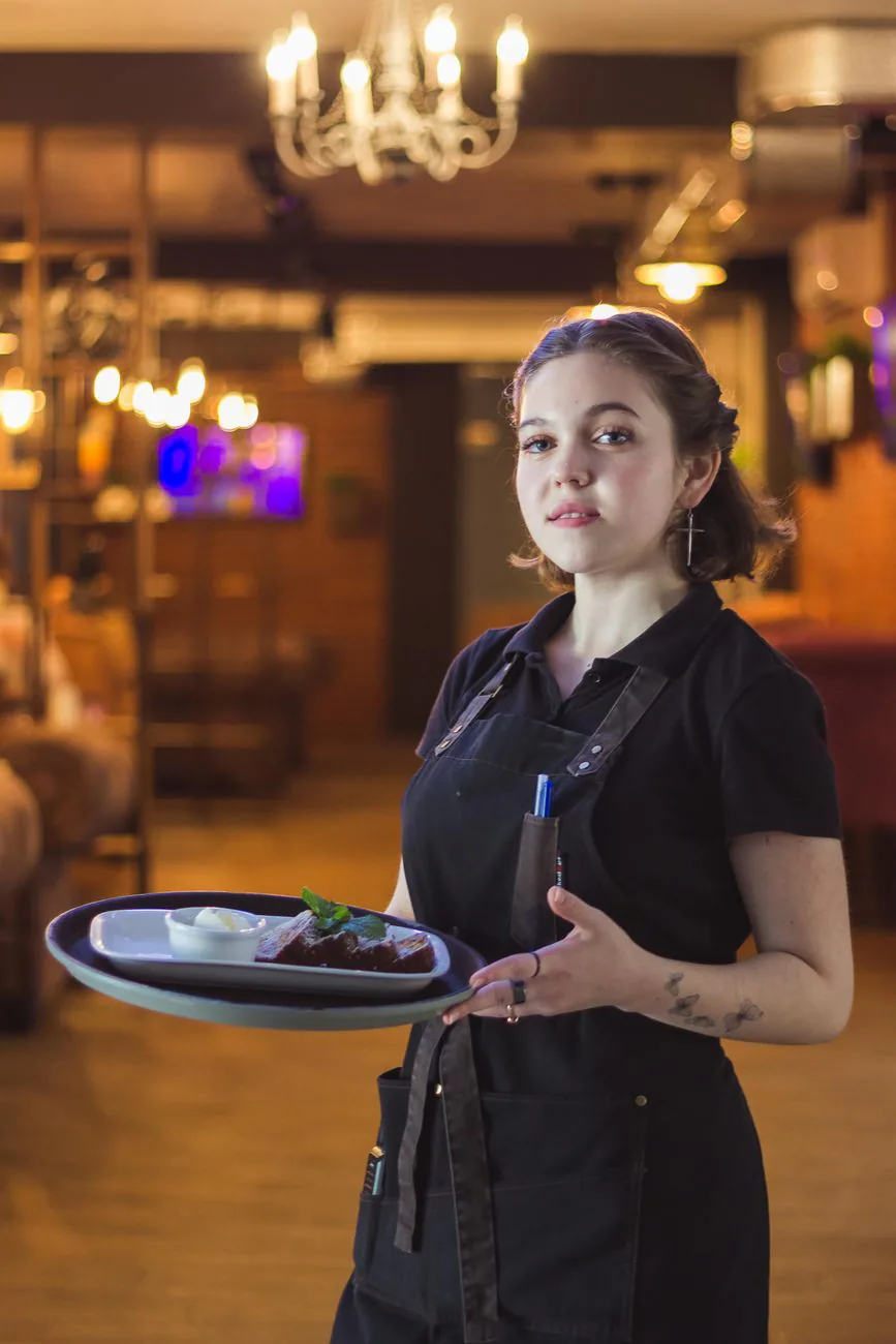 A server carrying a tray through the dining room