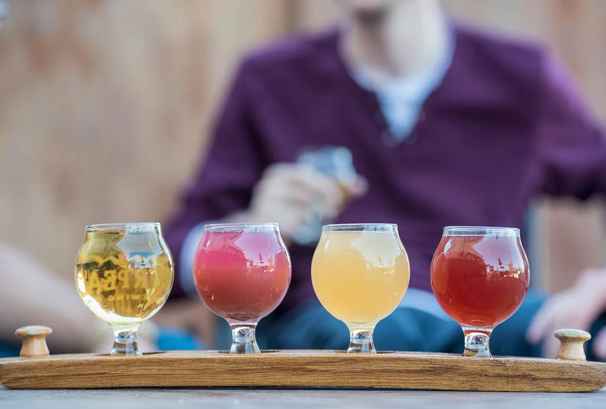 A flight of craft beers on a wooden tray