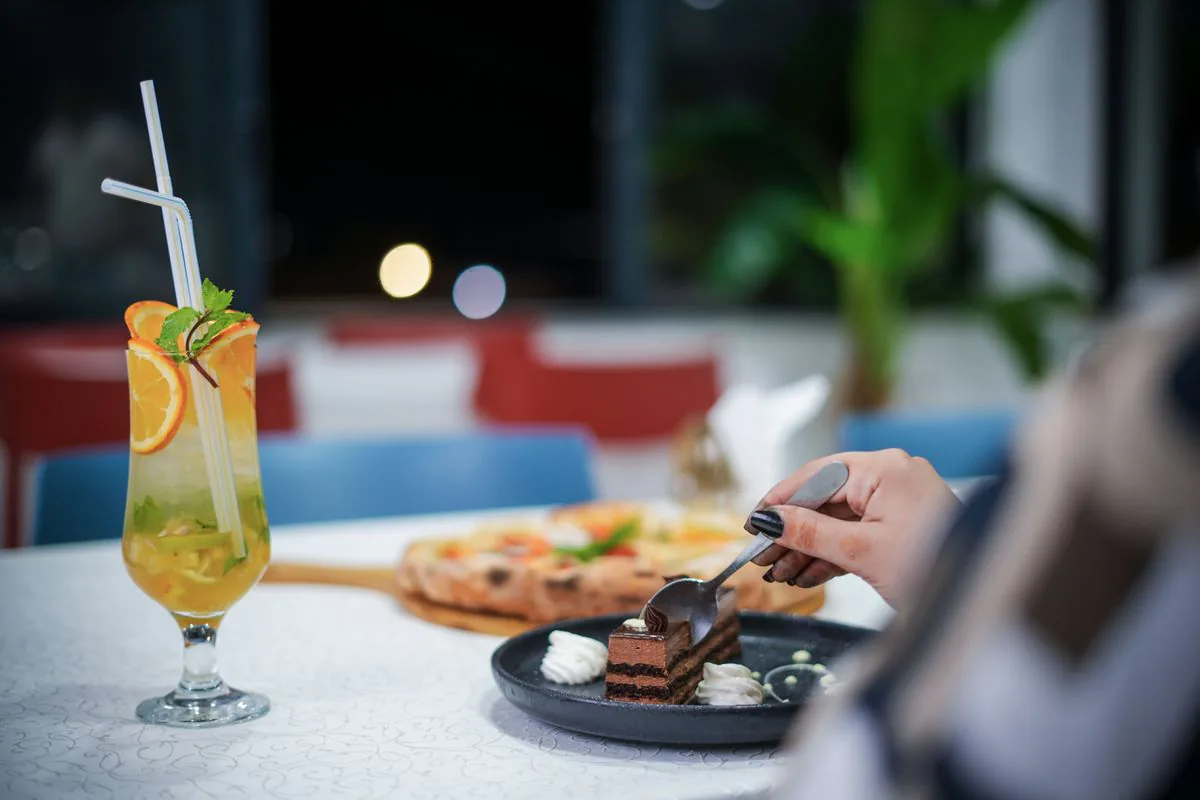 Slice of chocolate cake beside a cocktail