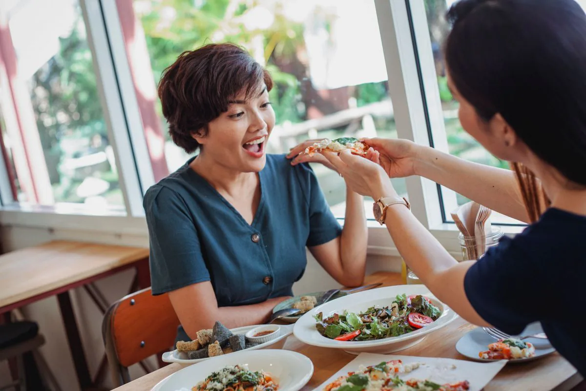 Friends sharing a slice of pizza at a tavern table