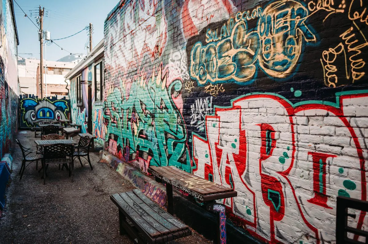 Colorful mural-covered alley with outdoor tables in the neighborhood