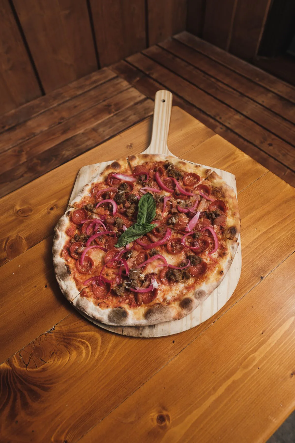 A gourmet pizza piled high with fresh toppings on a rustic wooden table
