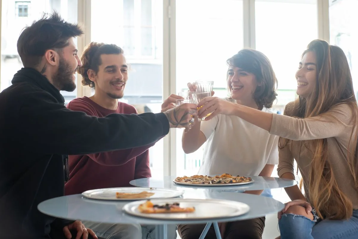 Friends reaching for slices of pizza at a lively dinner table