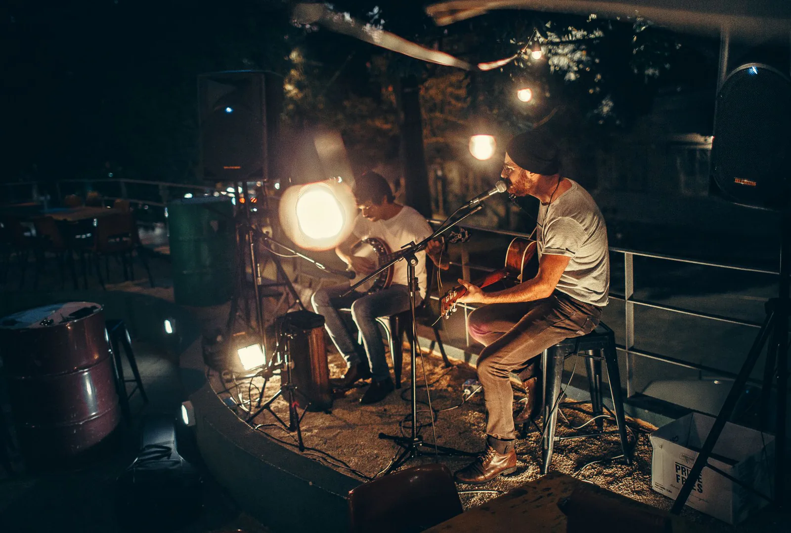 Two musicians playing acoustic sets on a lively evening