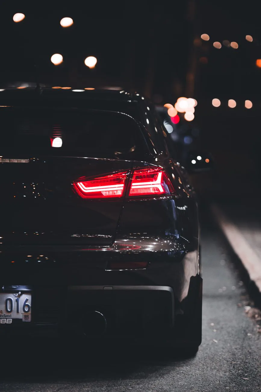 Rear view of a black sports car on a dark city street