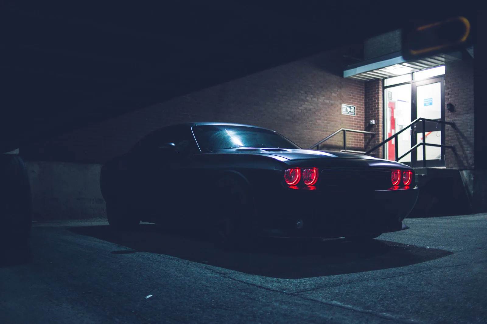 Low angle of a black car with glowing headlights at night