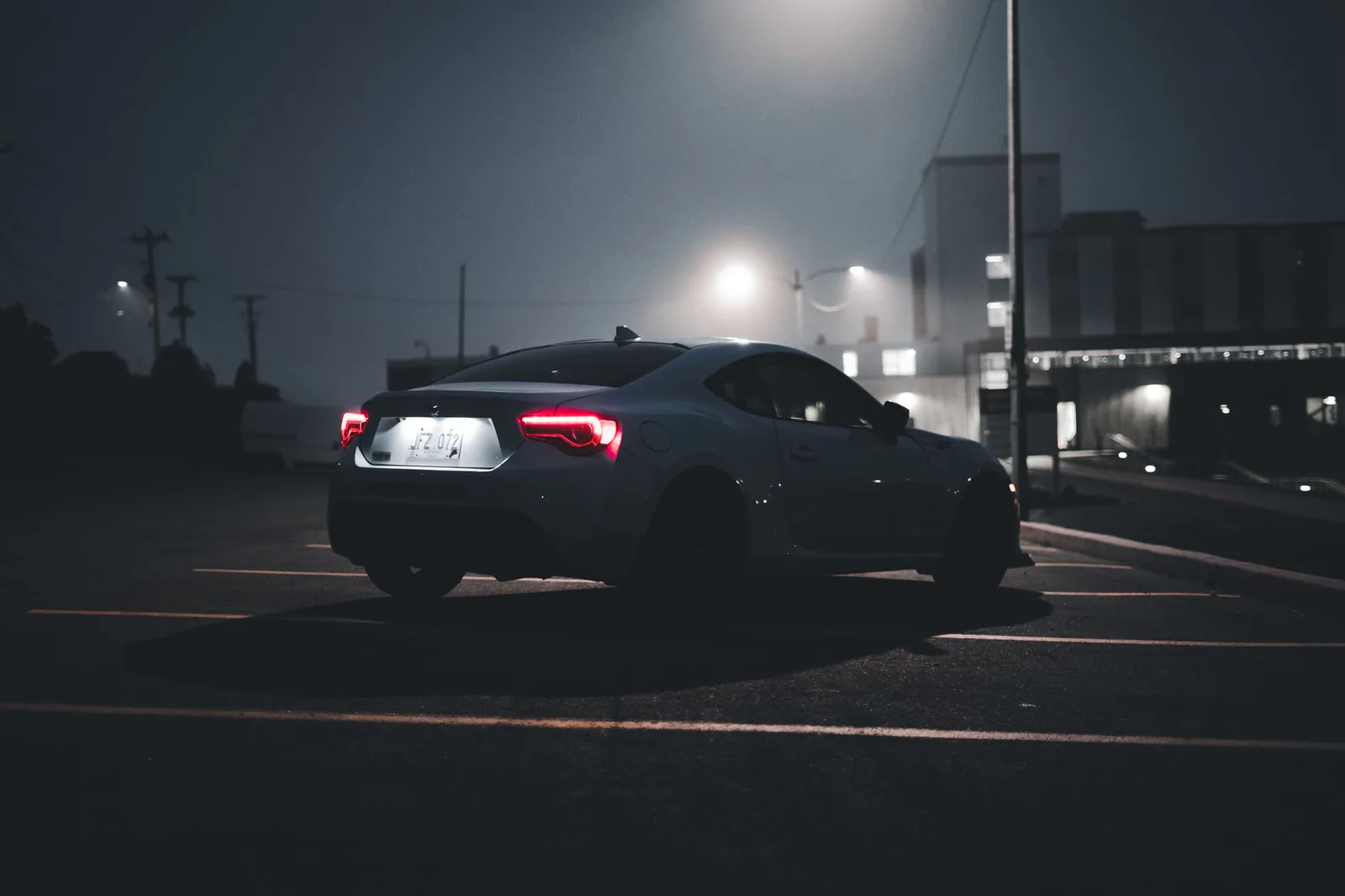 Sleek car with illuminated taillights in a dim parking lot