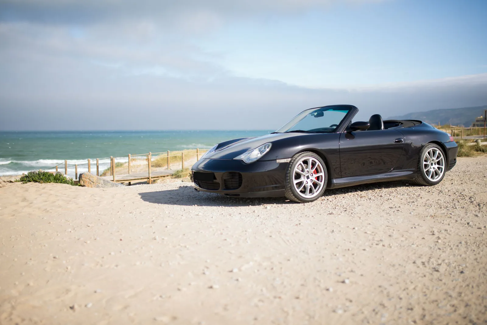 Black convertible parked on a sunny coastal beach road