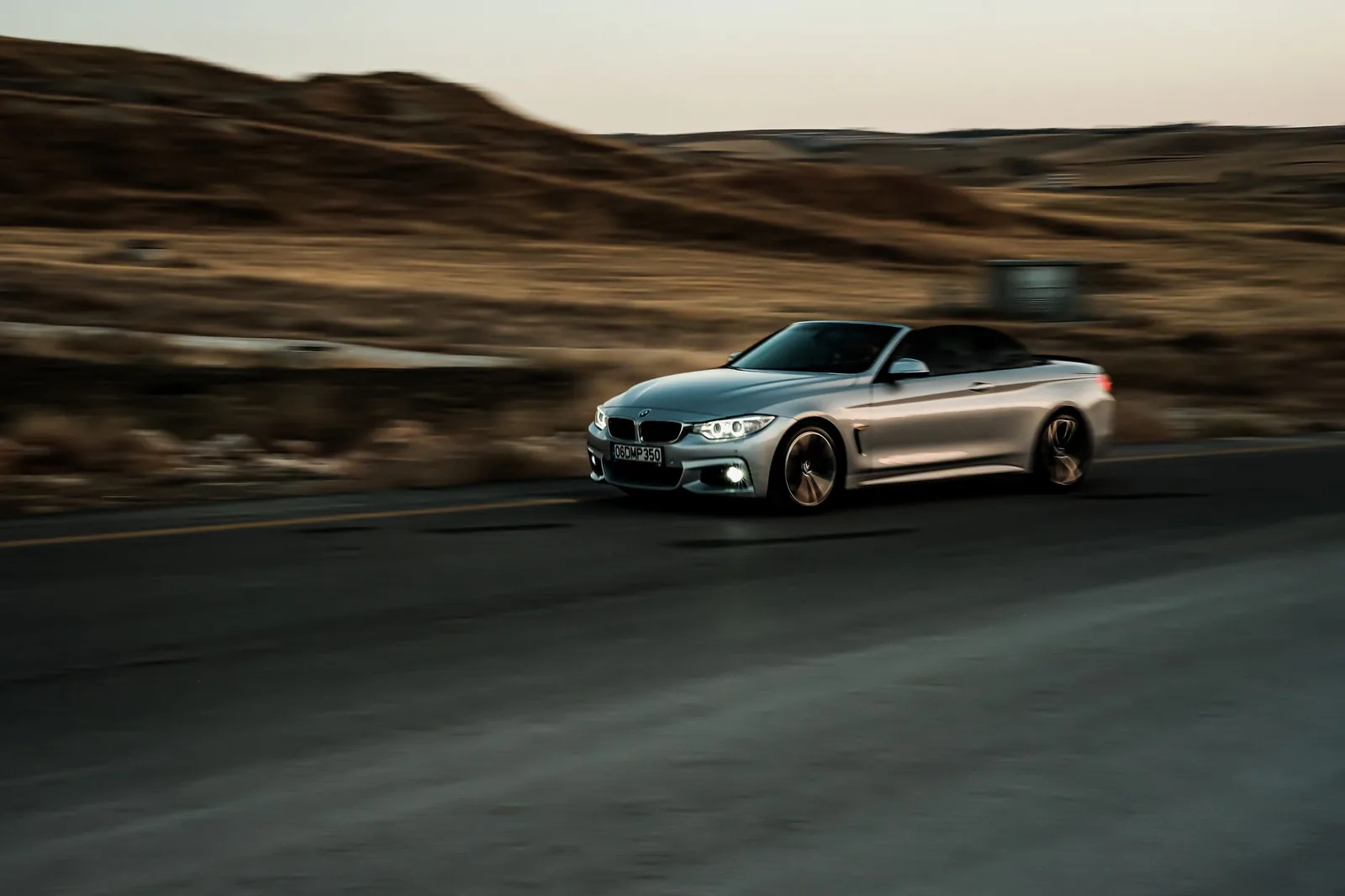 Silver luxury convertible moving along a coastal highway