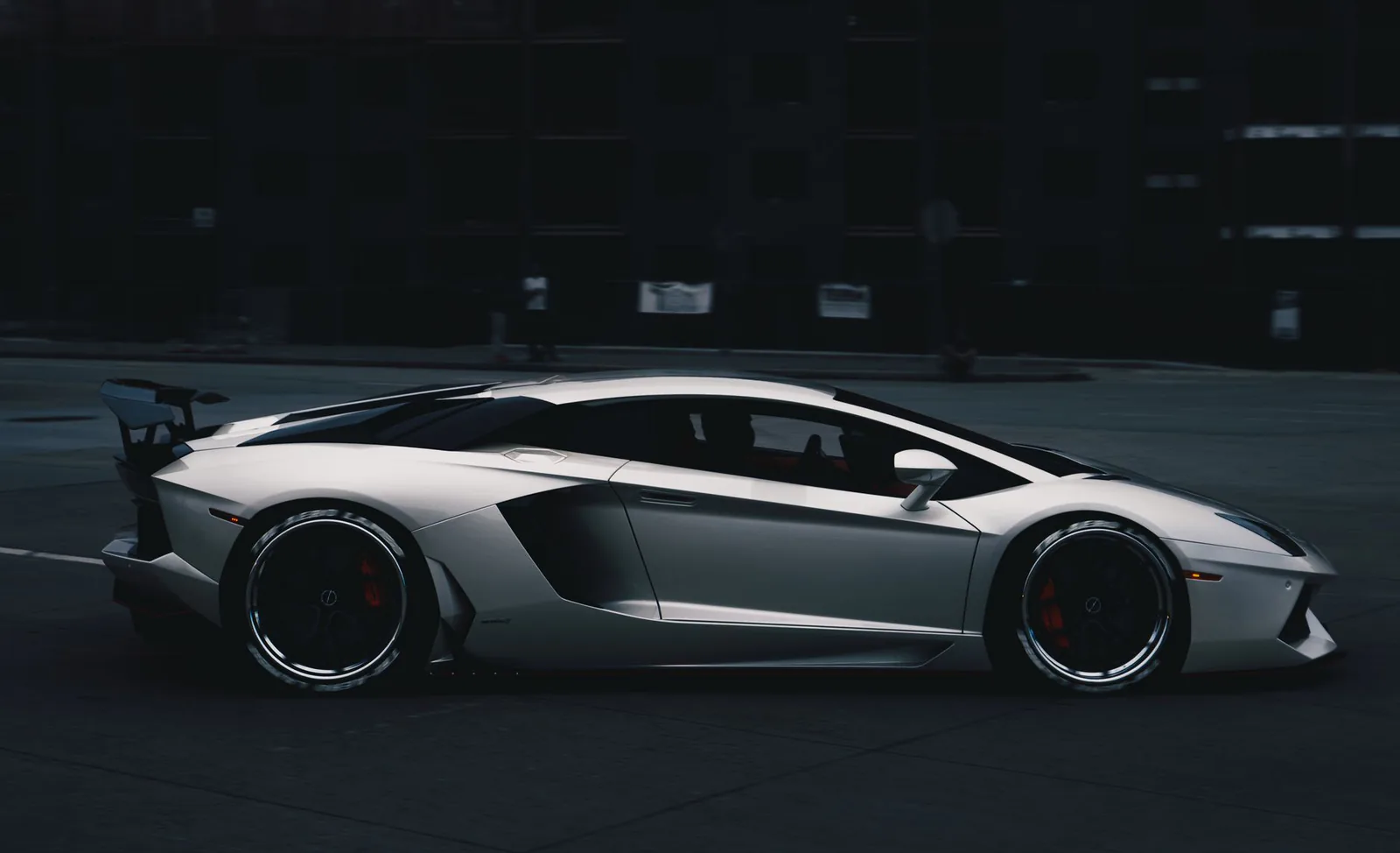 Lamborghini Aventador driving through city streets at night