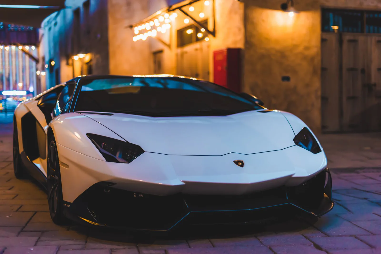White luxury sports car parked on a city street at night