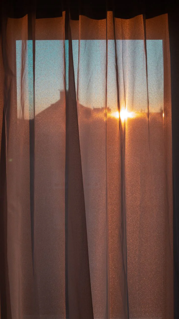 Golden morning light streaming through a linen curtain