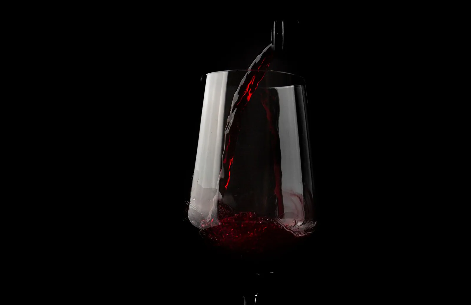Dramatic close-up of red wine being poured into a glass