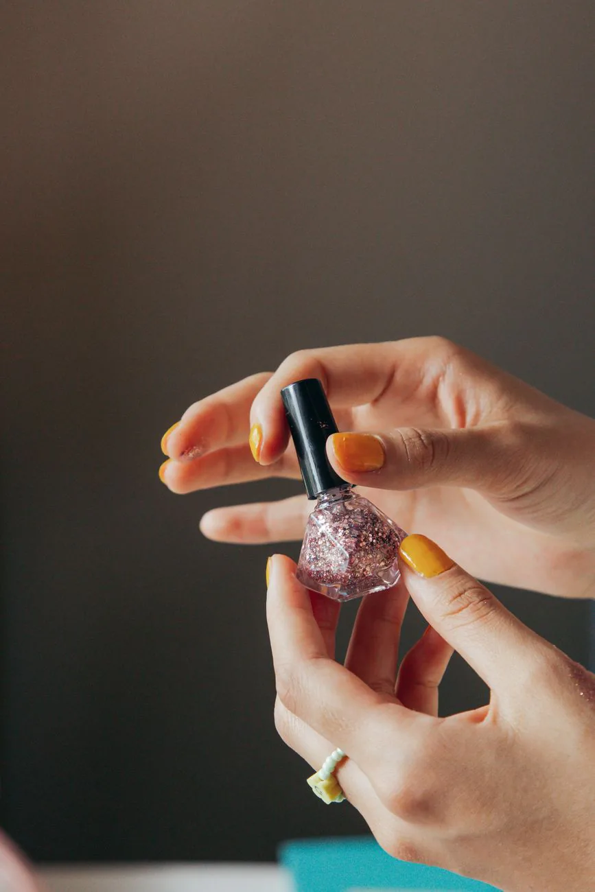 Manicured nails holding a glitter polish bottle