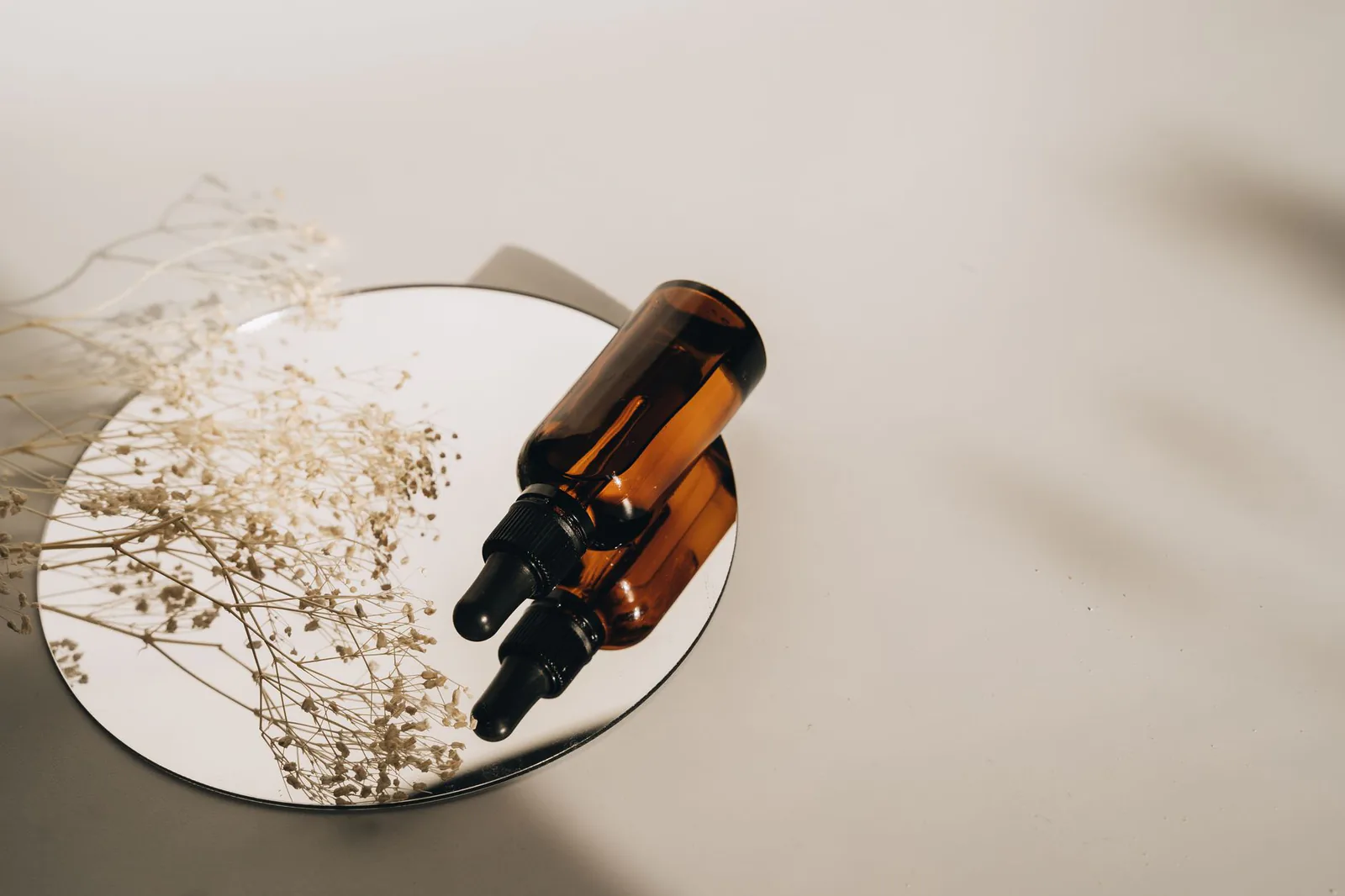 Minimal amber skincare bottles arranged on a mirror