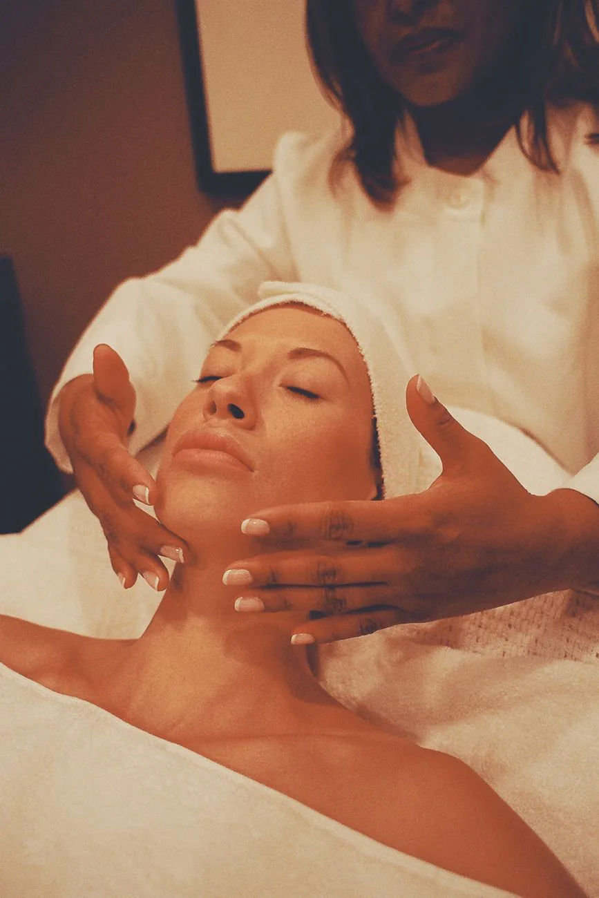 Hands performing a facial massage in warm light