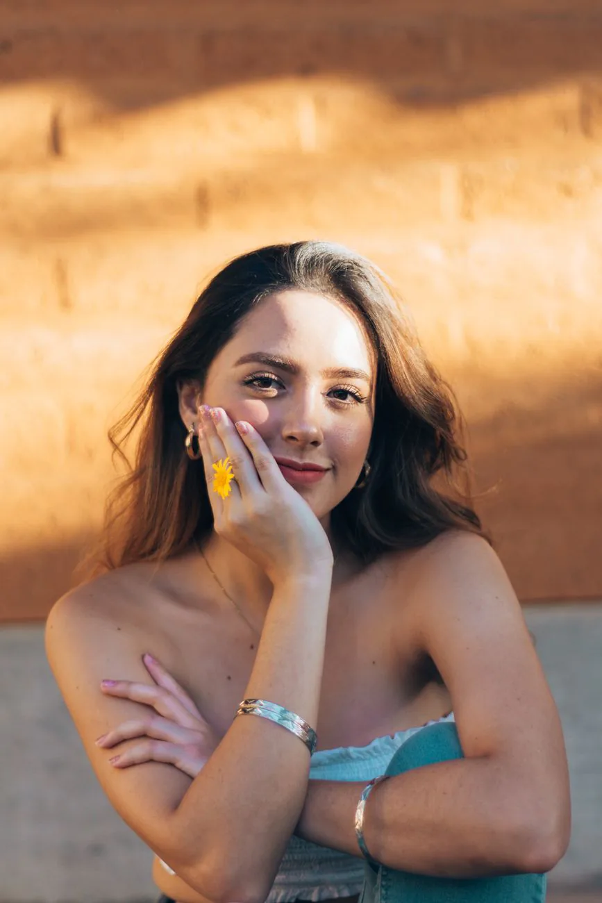 A woman in golden light holding a yellow flower