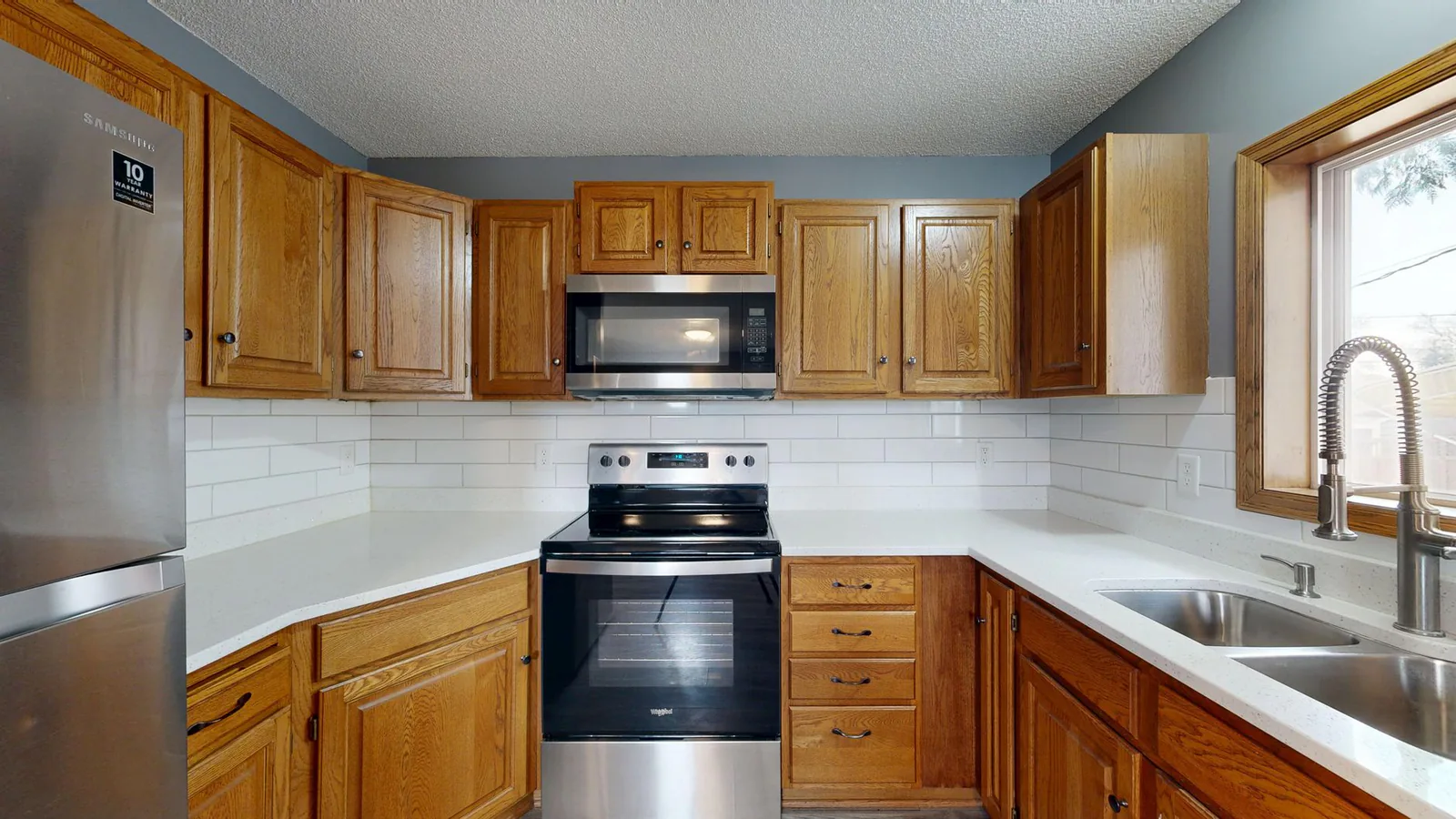 Kitchen after renovation — modern white oak cabinets and stone counters