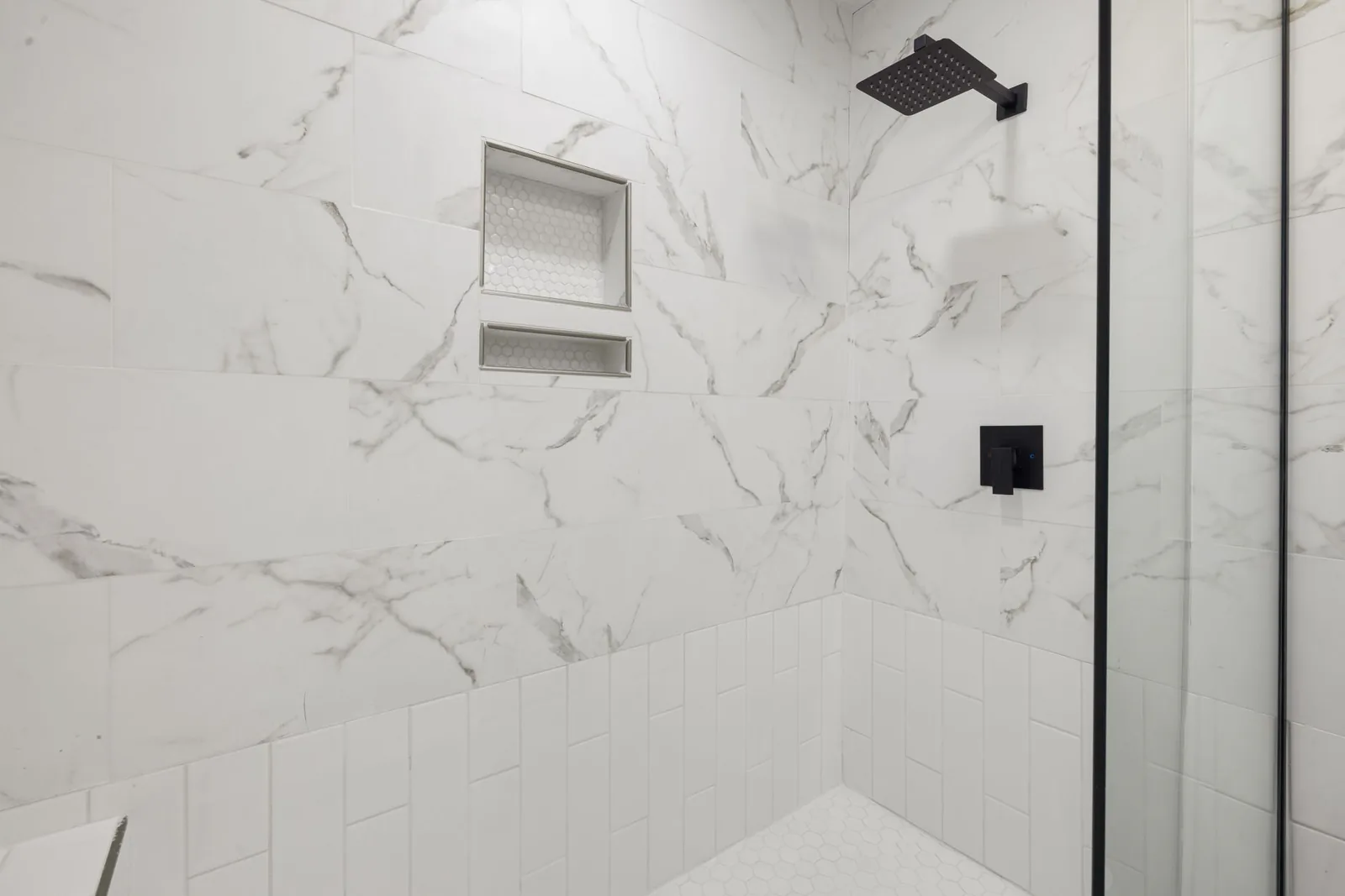 Renovated bathroom with marble tile shower and black fixtures
