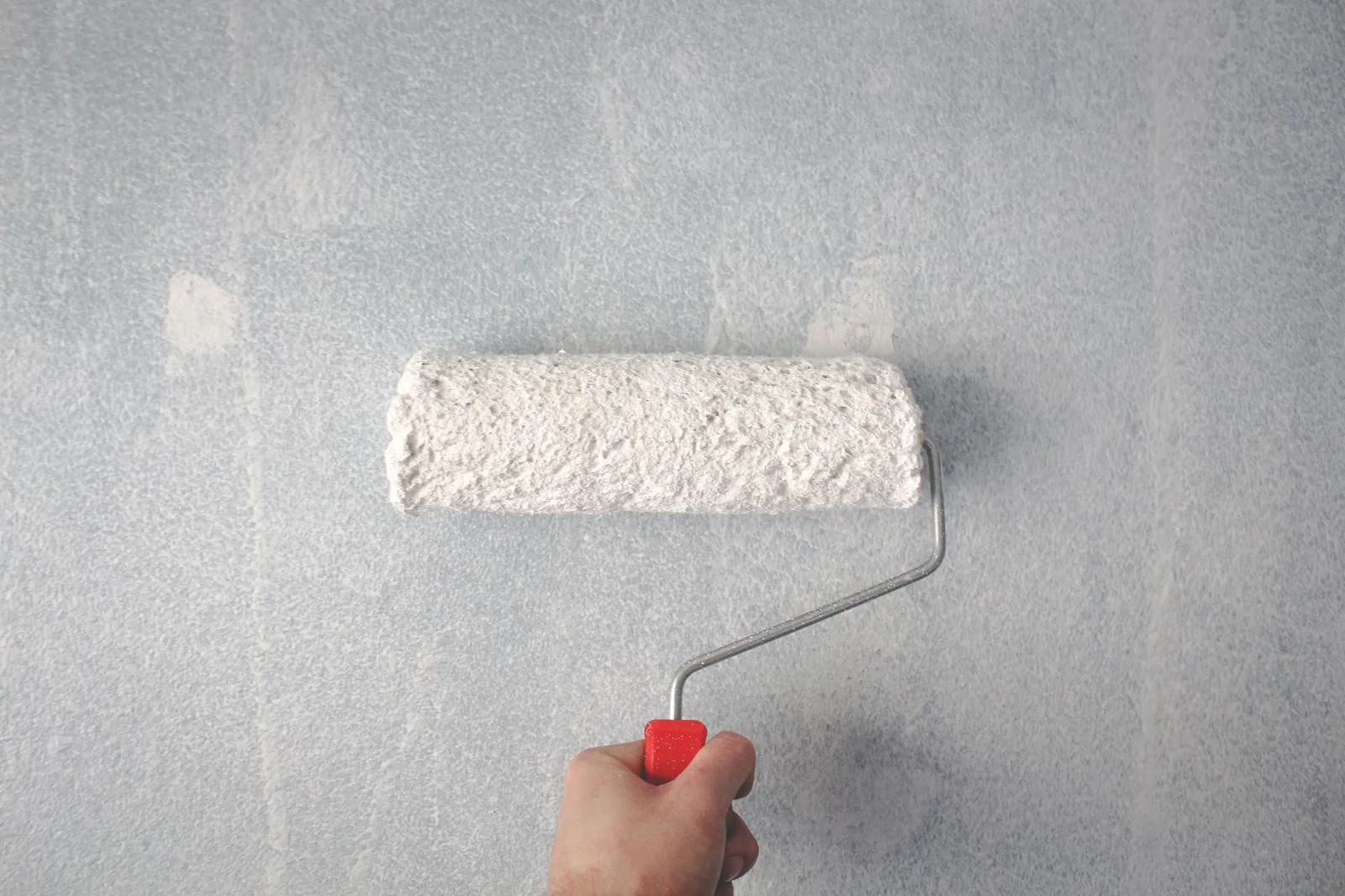 Fresh white paint being rolled onto an interior wall