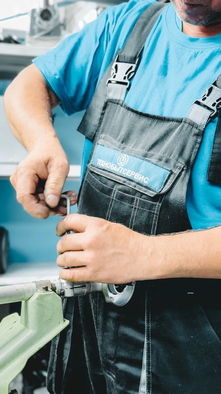 SDL Plumbing technician in a blue uniform tightening a fitting with a wrench