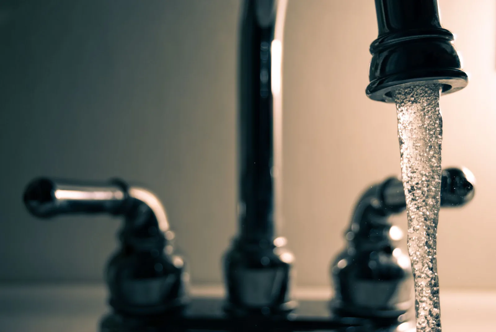 Water running from a stainless steel kitchen faucet over the disposal