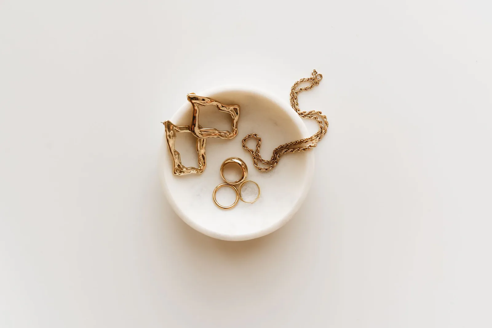 Gold jewelry arranged on marble