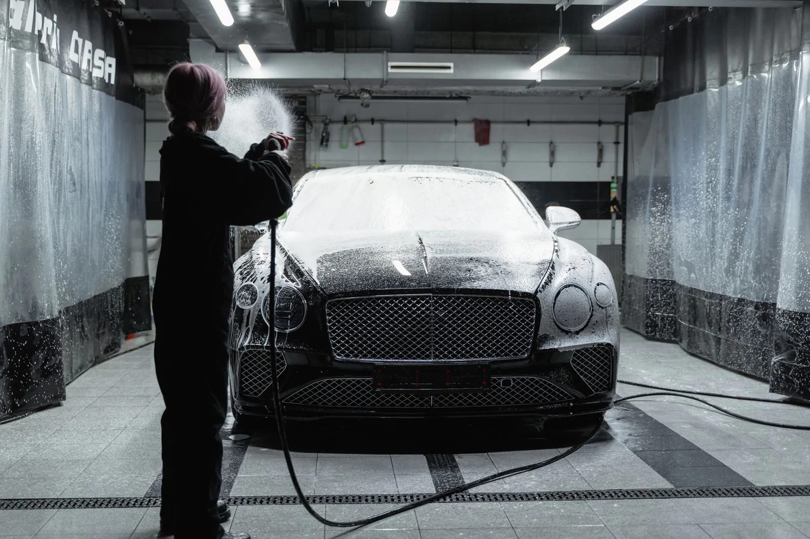 Professional hand wash being performed on a dark luxury sedan