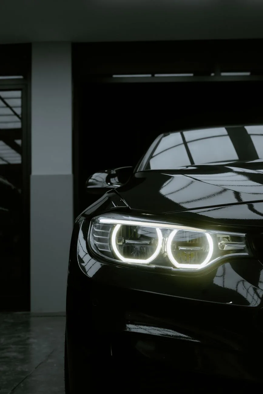 Black car with bright headlights in a dim garage