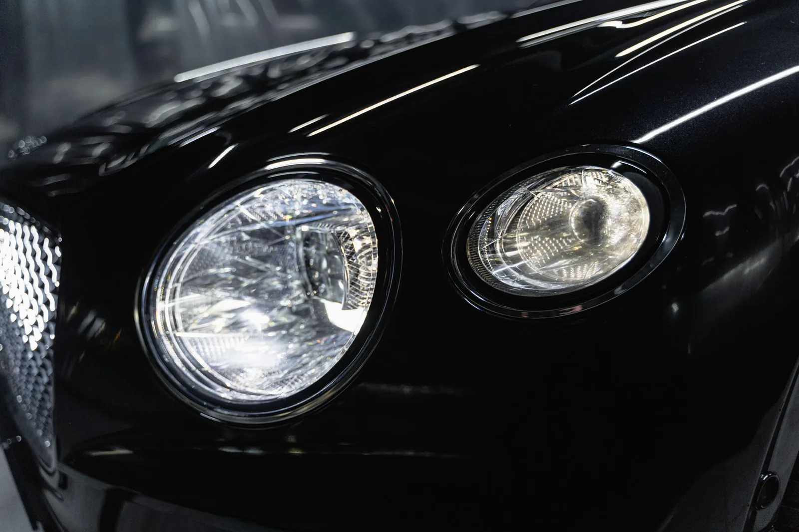 Polished black headlight with water droplets