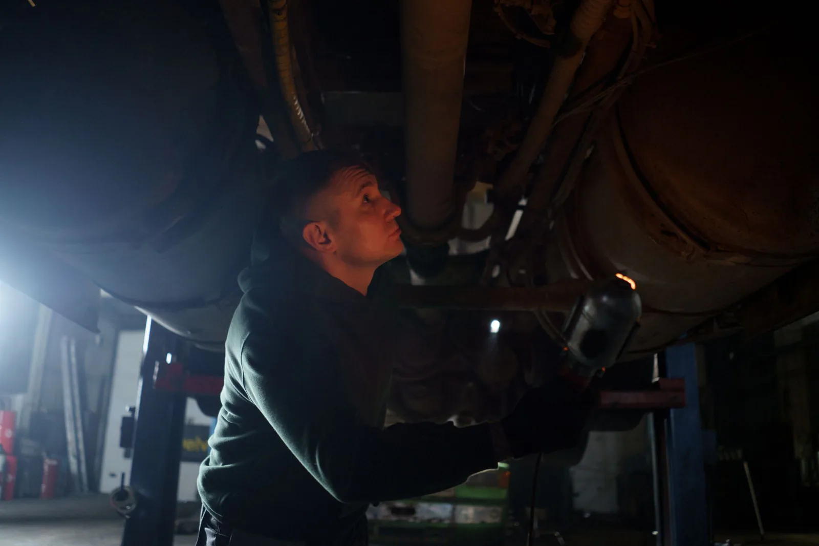 Technician inspecting a vehicle underbody in the shop