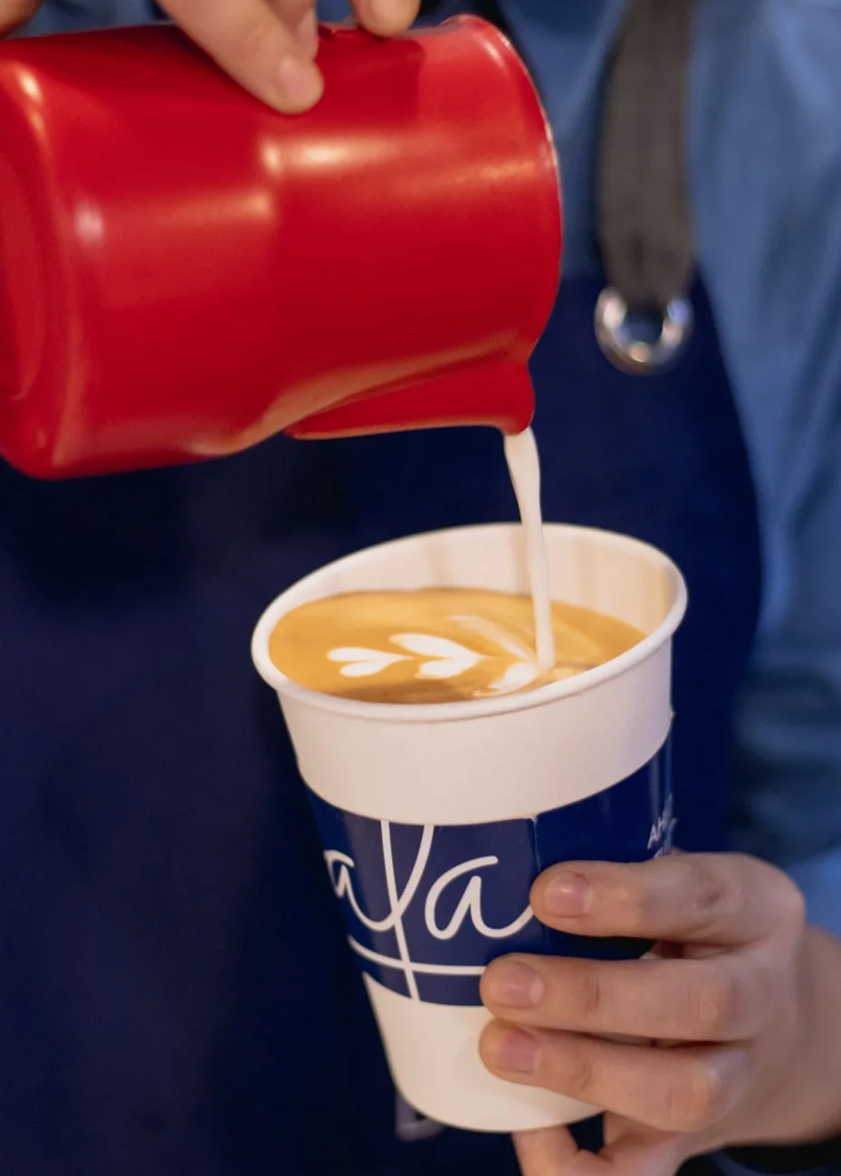 Latte art poured from a red pitcher