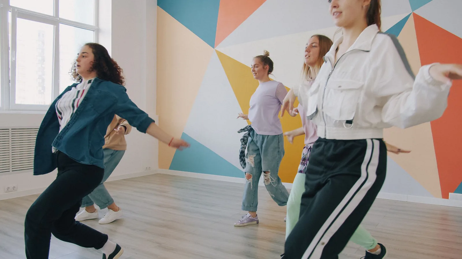 Four women dancing energetically in a modern Zumba studio